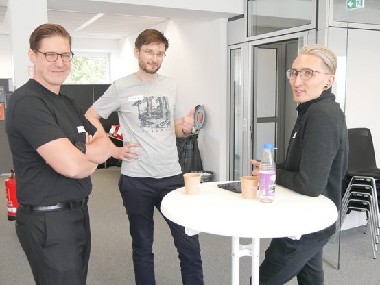 Teilnehmende im Gespräch am Stehtisch